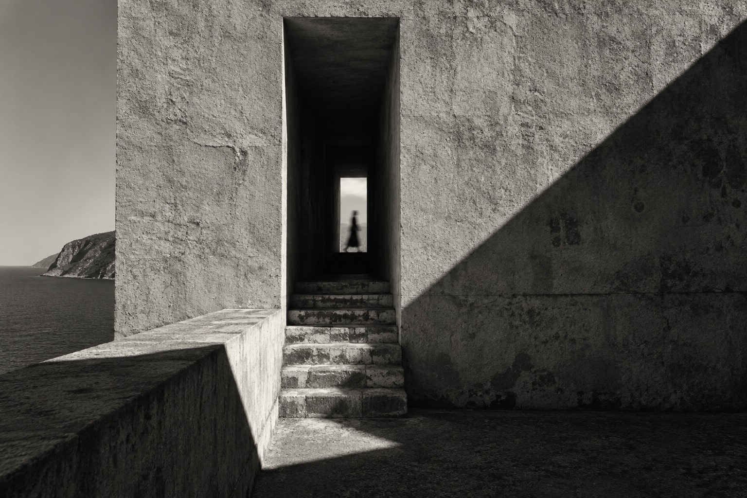 Un pasaje de hormigón, una escalera y una figura humana al fondo.